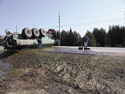 This tanker overturned on a two-lane state highway in Oconto County, Wisconsin when the driver got too far off on the shoulder and lost control. After creating a dam in the road ditch to contain the manure, employees scrape solids off the road as they prepare to remove the tractor and tanker from the highway and complete the cleanup. PHOTO SUBMITTED