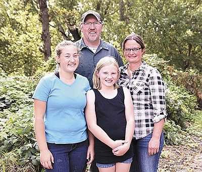 Brad and Shelley Schrandt, along with their daughters, Grace (left) and Callie, milk 90 cows on their dairy in Winona County near St. Charles, Minnesota.  PHOTO BY KIRSTA KUZMA