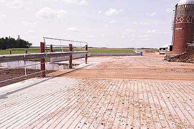 Concrete connects animal housing buildings and slopes toward the 1.4-million-gallon pit to collect any runoff at the Curriers’ farm near Mantorville, Minnesota. PHOTO BY KRISTA KUZMA