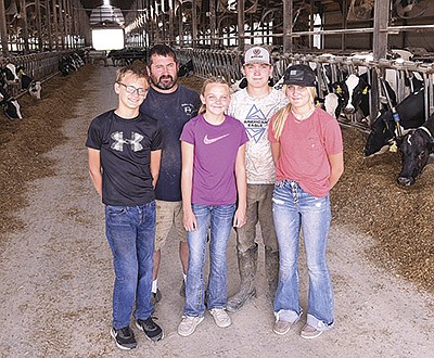 Cory Mulhern (back row, left) stands with his children – (from left) Miles Tweten, Brynn Tweten, Riley Mulhern and Emma Mulhern – in one of the freestall barns at Mulhern Dairy, where the Mulherns milk 960 cows near Fountain, Minnesota. PHOTO BY KRISTA KUZMA