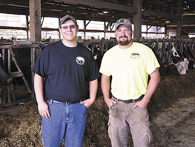 Zach Brand (left) and his boss, Nick Agrimson, stand in the freestall barn at Metz’s Hart-Land Dairy and Creamery near Rushford, Minnesota. The 17-year-old high school junior began working at the 190-cow dairy in June 2018.  PHOTO BY KRISTA KUZMA