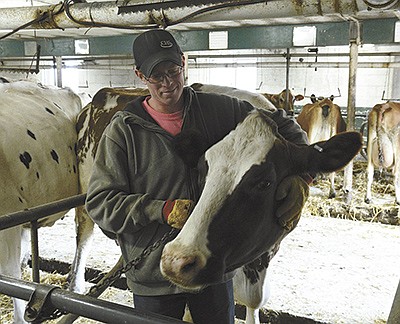 Adam Whiteaker poses with his favorite cow, Scarlet. Whiteaker milks 60 cows in a tiestall barn near Mantorville, Minnesota.  PHOTO BY KATE RECHTZIGEL