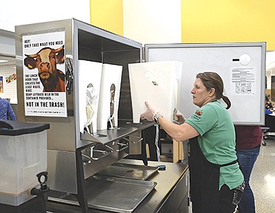 Hutchinson High School agriculture teacher Scott Marshall (left) and dairy farmer Leah Kurth (right) help students use the milk-dispensing machine at the high school Feb. 1 in Hutchinson, Minnesota. The McLeod County ADA helped sponsor the new machine. PHOTO BY JENNIFER COYNE