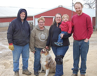 Mark Troester (from left), Rondee Troester, Anna Wilson holding Lewis and David Wilson milk 95 cows at the Troesters’ farm in Clayton County near Garnavillo, Iowa. The Wilsons were recently named Clayton County’s 2022 Outstanding Young Producers. PHOTO BY SHERRY NEWELL