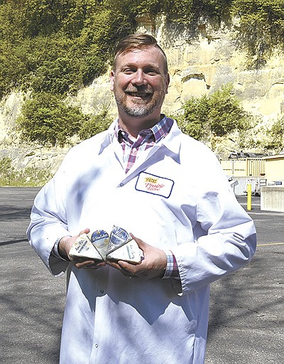 Rueben Nilsson stands with four wedges of blue cheese by the Caves of Faribault cheese plant and the sandstone bluff May 23 in Faribault, Minnesota. The plant produces 3.5 million pounds of cheese a year and is owned by Prairie Farms of Edwardsville, Illinois.  PHOTO BY KATE RECHTZIGEL