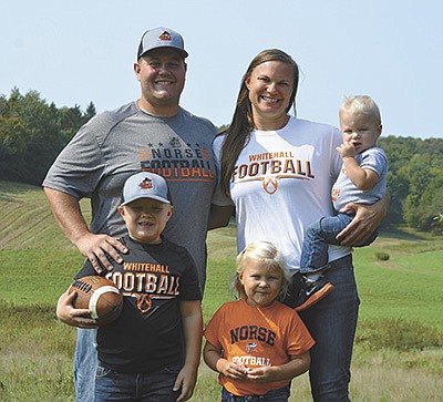 The Bortle family – Huck (front, from left) and Hollis; (back) Tyler and Callie, holding Hacher – stand on their farm Sept. 14 near Whitehall, Wisconsin. The Bortles milk 50 cows, and Tyler coaches high school football.  PHOTO BY ABBY WIEDMEYER