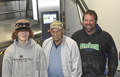Jordy (from left), Eugene and Joel Middendorf stand by the robotic milking system Oct. 20 on their farm near Melrose, Minnesota. The Middendorfs milk 113 cows in a tiestall barn and with a robot. PHOTO BY MARK KLAPHAKE