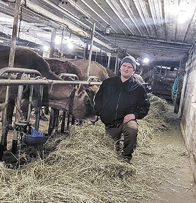 Levi Ulrich kneels in front of his cows on his Price County dairy farm near Ogema, Wisconsin. Ulrich milks 24 Jersey cows. PHOTO SUBMITTED