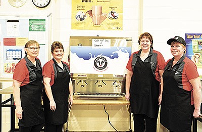 Sandy Boeckermann (from left), Lisa Yurczyk, Jackie Wolbeck and Alice Westrich show off the bulk milk dispenser Jan. 17 at Upsala Area Schools in Upsala, Minnesota. Westrich, head cook for the school district, was the main advocate for getting the dispenser. PHOTO BY TIFFANY KLAPHAKE