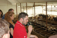Matt Goblirsch shows visitors the 250-cow freestall barn from the catwalk. Goblirsches designed their six-row freestall barn to be as labor efficient as possible. Slatted floors are scraped once a day, stalls have waterbed mattresses and side wall curtains are on a sensor system that automatically adjusts curtain height as weather changes. (Krista M. Sheehan)