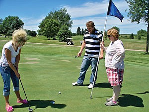 Janie Vanden Berg, who works at Pipestone Veterinary Clinic, lines up a putt while Nick and Ingrid Jopson watch during the 2011 Central Plains Golf Outing. Ingrid was later awarded a lawn chair and a cow bell for her golfing skills. (photo by Jerry Nelson)