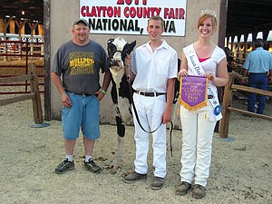 Matt Henkes (middle) was the People’s Choice Winner of the Celebrity Dairy Show. Henkes had the most monetary support from the audience to win the honor. He is shown with his sponsor, Bruce Olson (left) of Olson’s Hooftrimming, and Iowa Dairy Princess, Kendra Moser (right), presenting a banner to Henkes. (photo by Heidi deGier)