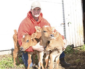 Josh Wolbeck holds his three Jersey calves that were born Sept. 22 on his farm near Sauk Centre, Minn. (photo by Amanda Bertram)