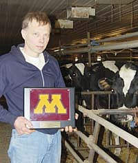 Don Settergren, who milks near Dassel Minn., holds the plaque he received 40 years ago after the Gopher Men’s Basketball team he managed in 1971-1972 took the championship title. Photo by Emily Lahr