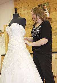 Laura Fellbaum switches wedding dresses on one of many mannequins throughout the shop. The Fellbaums have enjoyed the challenge of owning their own business in an industry completely different than dairy. But at the end of the day, Laura said, it’s nice to exchange her dress clothes for jeans and barn boots.<br /><!-- 1upcrlf -->PHOTO BY JENNIFER BURGGRAFF