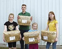 Allison, Cody, McKenna and Breanna Wright hold miniature straw bales their family markets to garden centers in the Twin Cities. The Wrights began this business several years ago. The 9- by 10- by 22-inch bales are used for decorating and mulching, among other things.<br /><!-- 1upcrlf -->PHOTO BY RUTH KLOSSNER