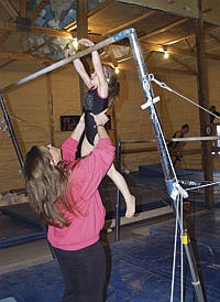 Meghan helps a gymnast onto the uneven bars during a practice on Jan. 7. <br /><!-- 1upcrlf -->PHOTO BY KRISTA SHEEHAN