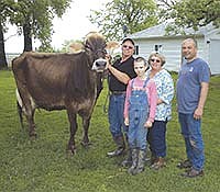 Les (left) and Jo (second from right) Olson’s cow, Thane Jesse Vigor Jessa, won the top protein and top production award in the Brown Swiss breed. The Olsons, who are pictured with son, Aaron, and grandson Brody, milk 275 cows on their farm near Spring Valley, Minn. <br /><!-- 1upcrlf -->PHOTO BY KRISTA KUZMA