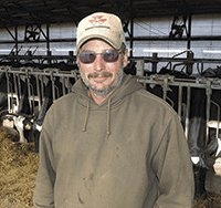 Jim Woodard stands in the freestall barn on his 90-cow dairy near Winona, Minn. Nearly one year ago Woodard suffered a stroke, which kept him out of the barn for four months. <br /><!-- 1upcrlf -->PHOTO BY KRISTA KUZMA