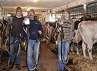 Ken (center) carries the milking units into the barn with two of his sons, William III (right) and Derek (left) on Jan. 2. Ken, William III and Derek milk together on their farm near Chaska, Minn. <br /><!-- 1upcrlf -->PHOTO BY MISSY MUSSMAN