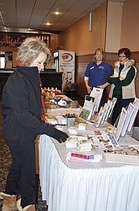 Kathi Molitor (left), Lisa Maus (center) and Sharon Salzer (right) look at the table of prizes and promotional information before the Midwest Dairy Association’s annual district meeting on Jan. 10 in Albany, Minn. <br /><!-- 1upcrlf -->PHOTO BY MISSY MUSSMAN
