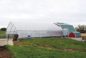 From the outside, the greenhouse milking parlor on the Kevin and Mary Jahnke farm looks much like a hoop calf barn. Its shell is two layers of plastic, with air blown between them. The parlor adjoins a solid-walled milkhouse building. Jahnke provided all the labor for the structures and built them for about $30,000 eight years ago. (photo by Ron Johnson)