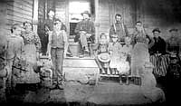 A yellowed photograph from about 1890 shows the Mitchell family gathered by the front porch of the farmhouse. John’s grandfather, Oliver, is seated in the middle. Photo submitted