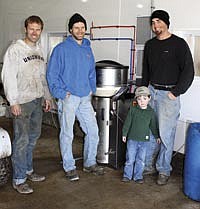 Chris (left) and Shawn (second from left) Gibbs are pictured with their employee Bob Mettille and his son in front of their automatic calf feeder. The Gibbs family, who has been using the system for six months, milk about 380 cows on their farm near Waterville, Iowa. <br /><!-- 1upcrlf -->PHOTO BY KELLI BOYLEN